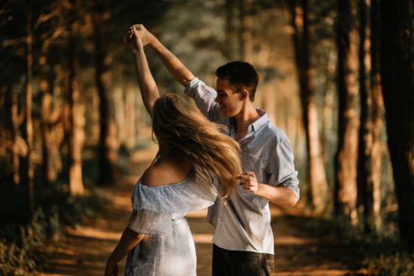 A couple dancing together in a woodland setting, surrounded by trees